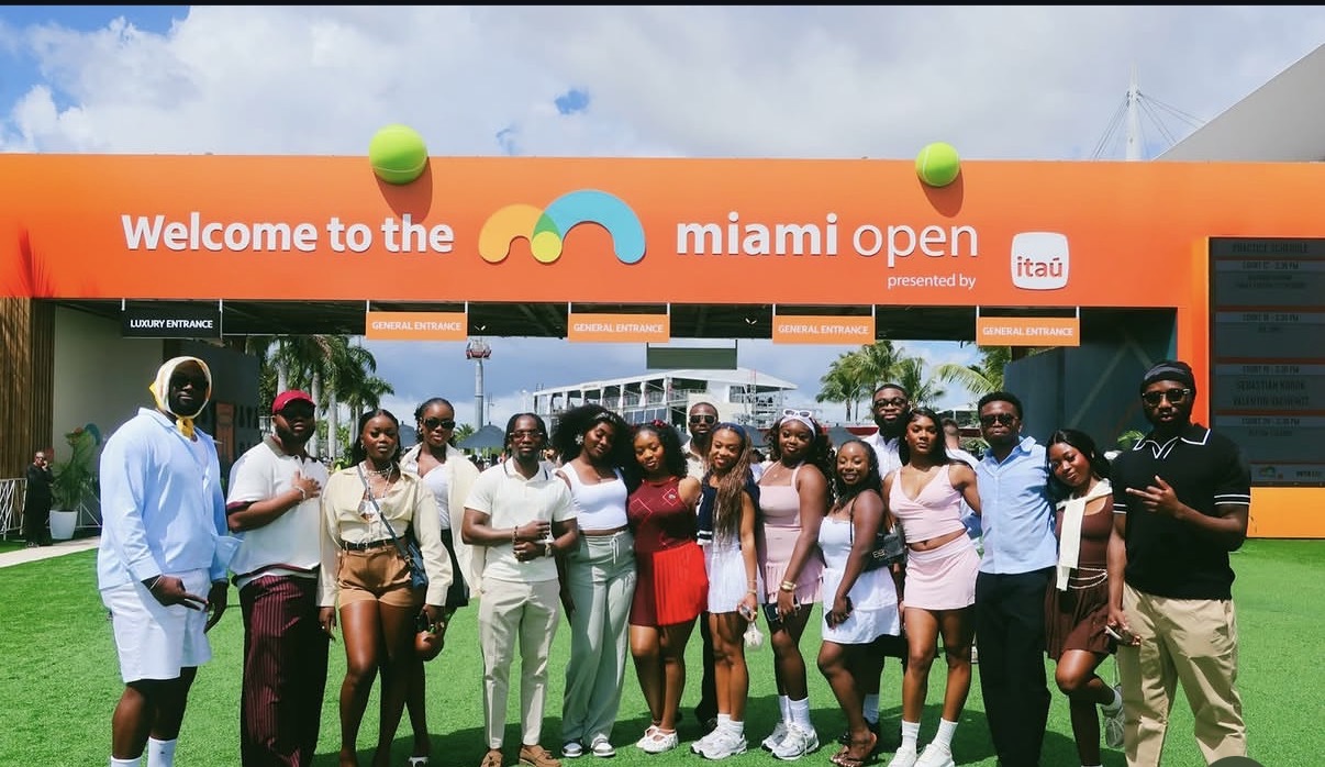 A JaiyeBoyz group posing together at the Miami Open entrance on a sunny day
